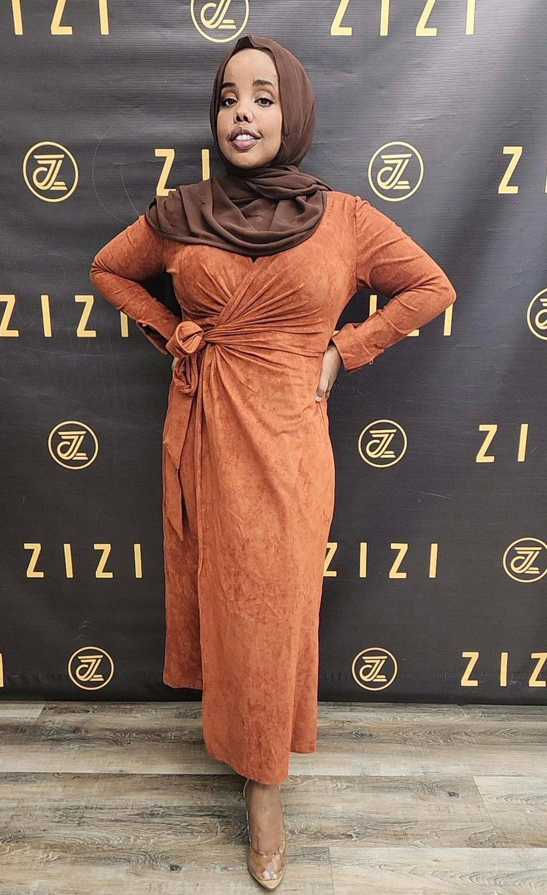 A person wearing an orange light suede wrap dress with a belt