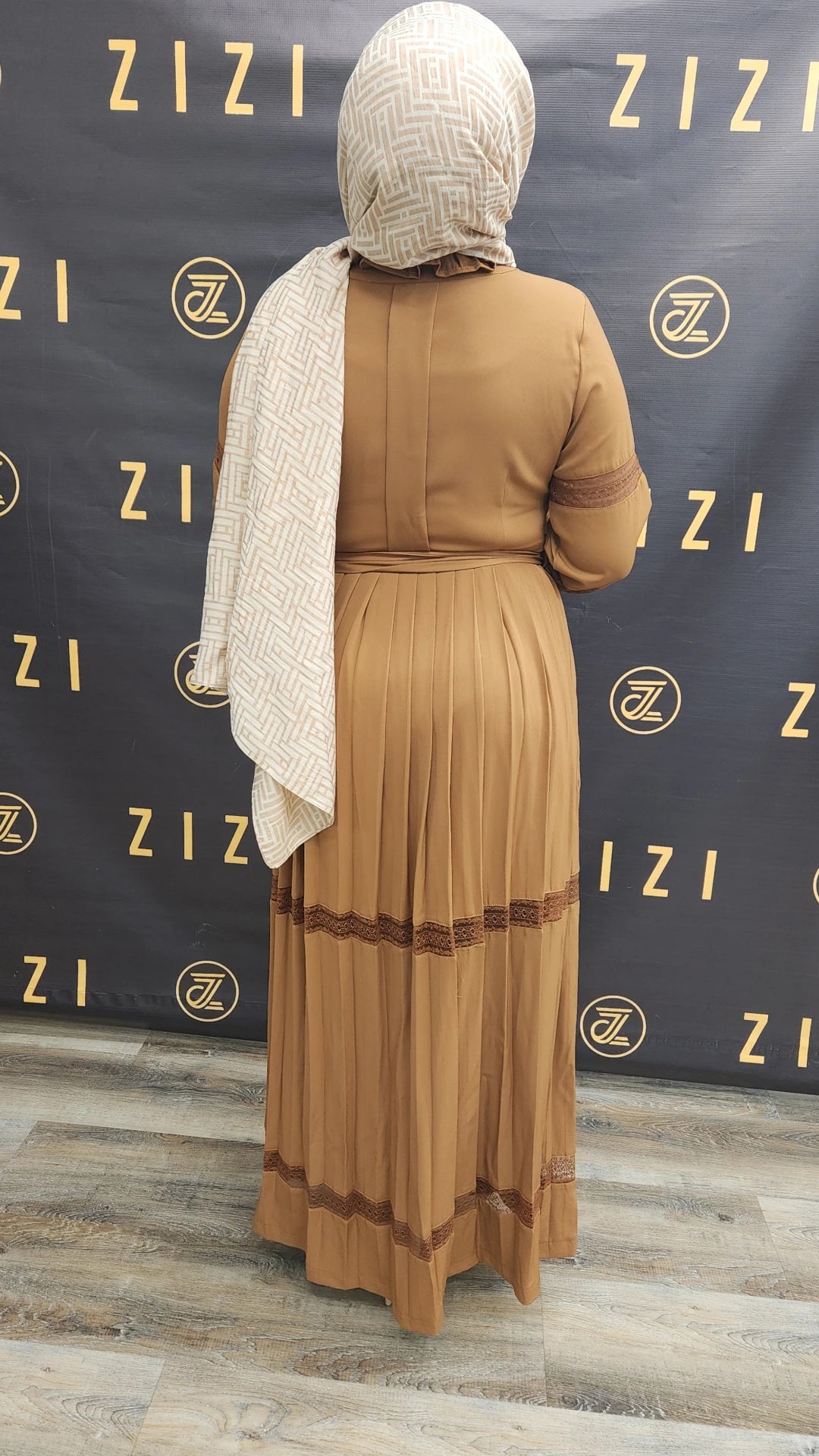 Back view of woman wearing Hodan Lace Maxi Dress in brown from ZIZI Boutique with pleated skirt and lace detailing