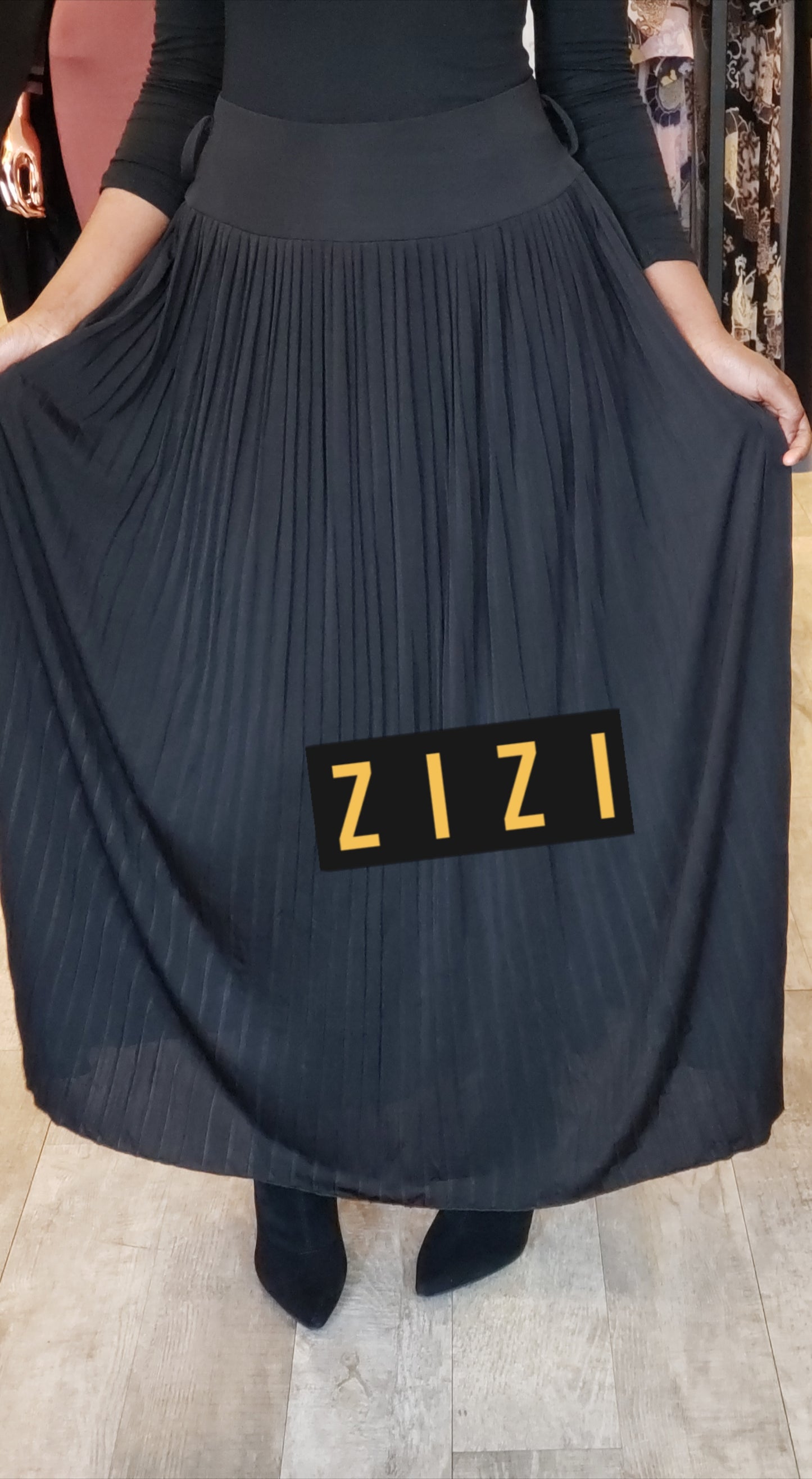 High waisted women's maxi pleated skirt in black worn with black top and boots