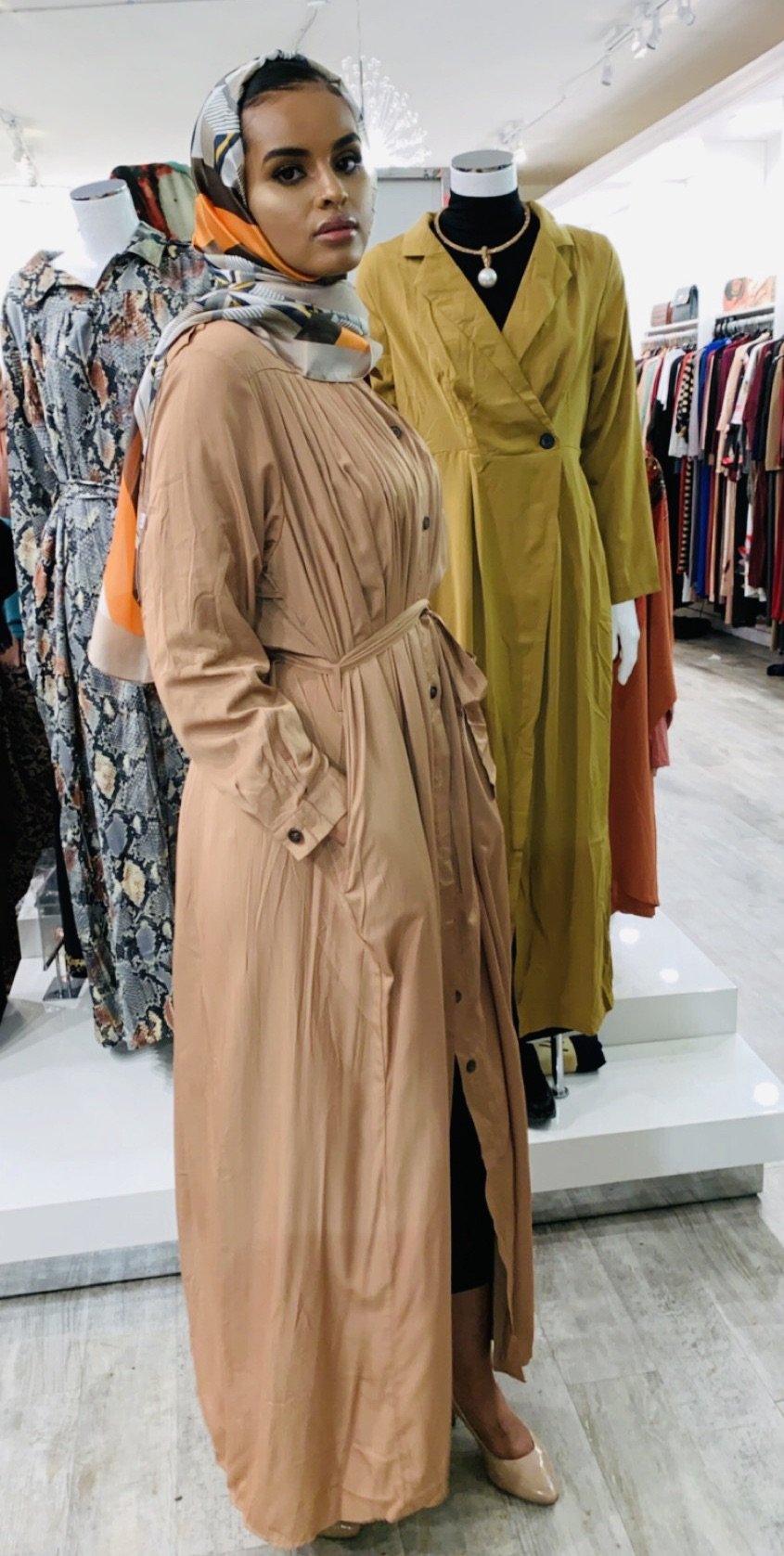 Woman wearing a beige Pleated Button Down Dress with long sleeves and a belt at ZIZI Boutique