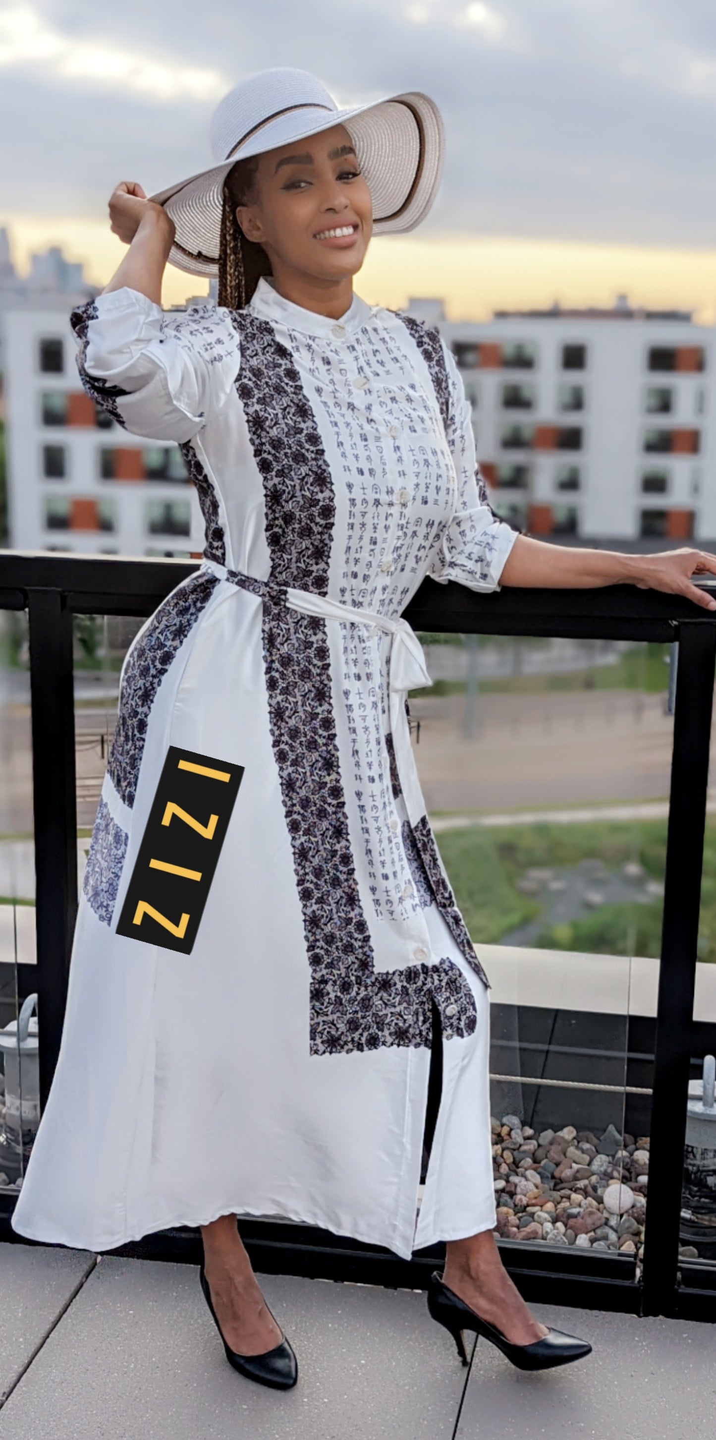 Woman wearing a Satin Silk Maxi Print Dress Shirt by ZIZI Boutique with black and white pattern and white hat