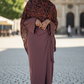 Woman in a brown dress with a patterned hijab standing on a cobblestone street.