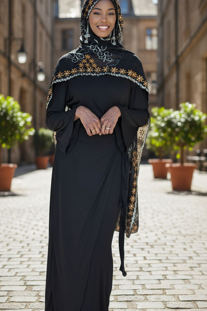 Woman in modest wrap dress wearing a hijab with intricate patterns standing on a street.