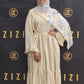 Woman in a beige dress with a floral headscarf standing in front of a ZIZI branded backdrop.