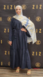 Woman in a navy blue dress with a patterned scarf standing in front of a Zizzi branded backdrop.