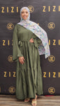 Woman wearing a green dress and floral hijab in front of a Zizi branded backdrop