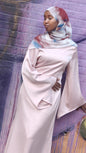 Woman wearing a pale pink Zalina Satin Maxi Dress from ZIZI Boutique with wide bell sleeves and a colorful hijab
