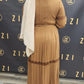 Back view of woman wearing Hodan Lace Maxi Dress in brown from ZIZI Boutique with pleated skirt and lace detailing