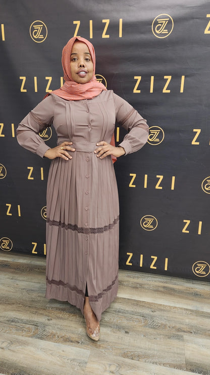 Woman wearing a Hodan Lace Maxi Dress in muted mauve color standing against ZIZI Boutique backdrop