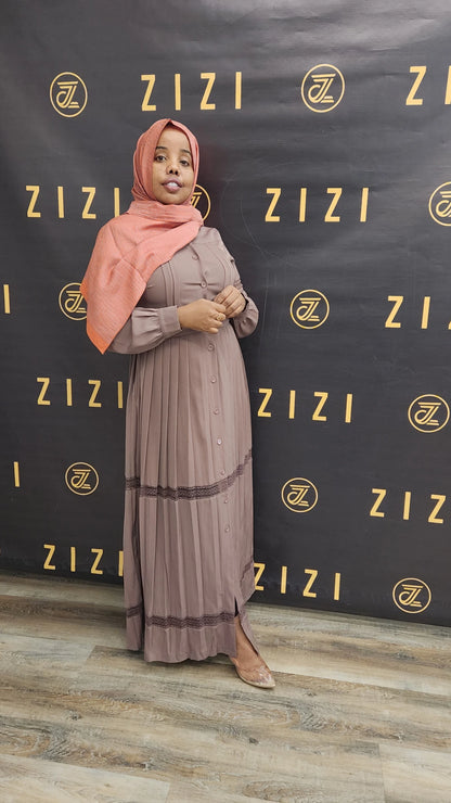 Woman wearing a taupe Hodan Lace Maxi Dress from ZIZI Boutique with a matching hijab posing indoors
