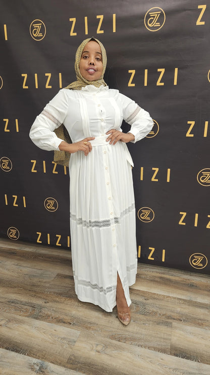 Woman wearing a white Hodan Lace Maxi Dress by ZIZI Boutique with lace details and a front slit