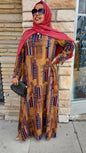 Woman wearing a Zoraa Summer Print Maxi Dress with geometric patterns in earth tones and a red hijab