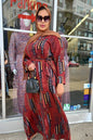 Woman wearing Zoraa Summer Print Maxi Dress in red geometric pattern with sunglasses and brown hijab outside a boutique