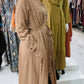 Woman wearing a beige Pleated Button Down Dress with long sleeves and a belt at ZIZI Boutique