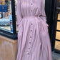 Woman wearing a light pink Pleated Button Down Dress with long sleeves and a fitted waist from ZIZI Boutique