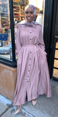 Woman wearing a light pink Pleated Button Down Dress with long sleeves and a fitted waist from ZIZI Boutique