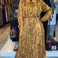 Woman wearing a brown patterned pleated button down dress with long sleeves and a belt at ZIZI Boutique