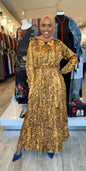 Woman wearing a brown patterned pleated button down dress with long sleeves and a belt at ZIZI Boutique