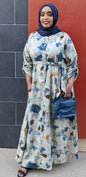 Woman wearing ZZ Linen Dess Multi Flowers Print long dress with blue floral patterns and carrying a navy blue handbag